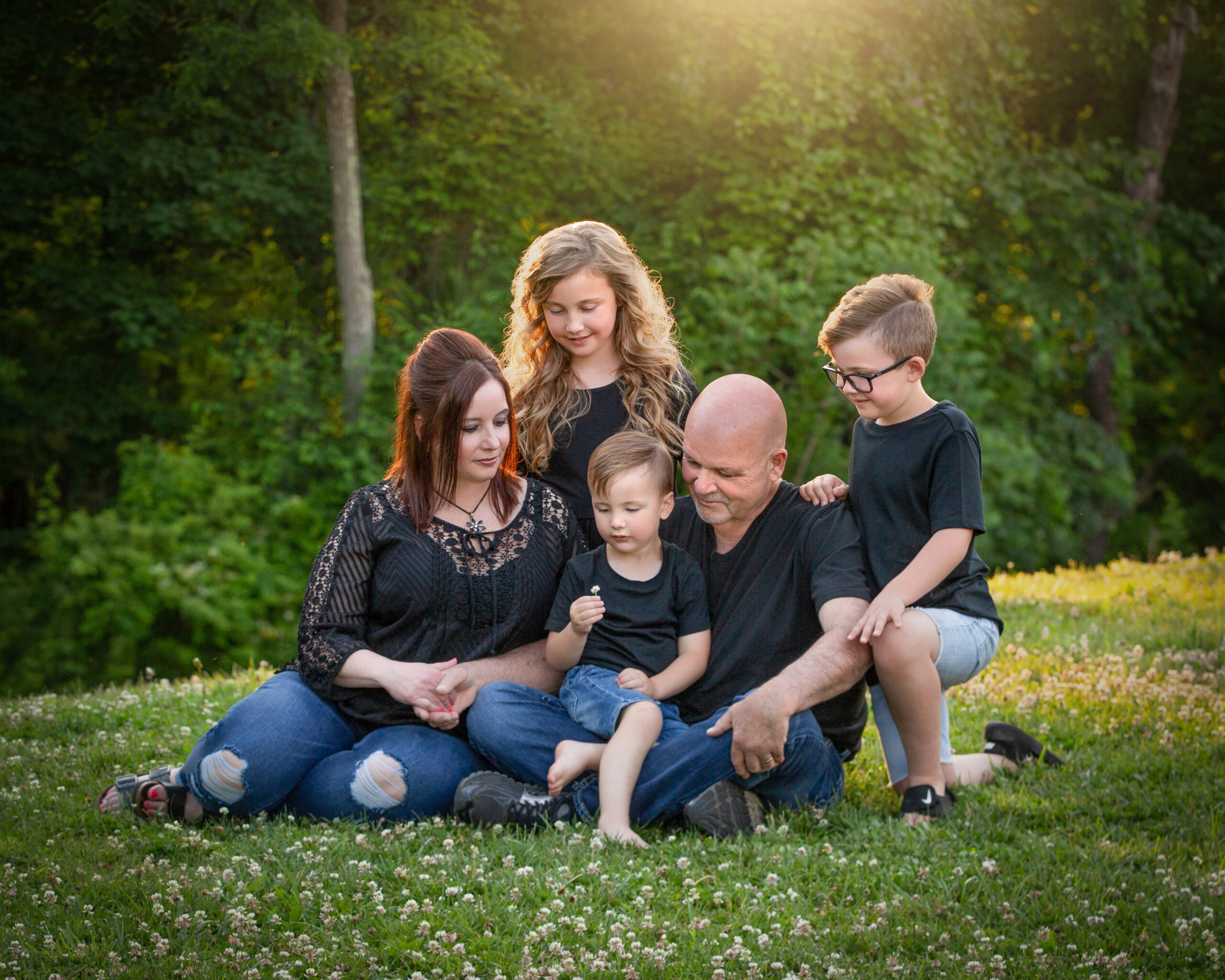 Grandparents sitting outdoors with their grandchildren in a heartfelt sunset family portrait surrounded by nature.