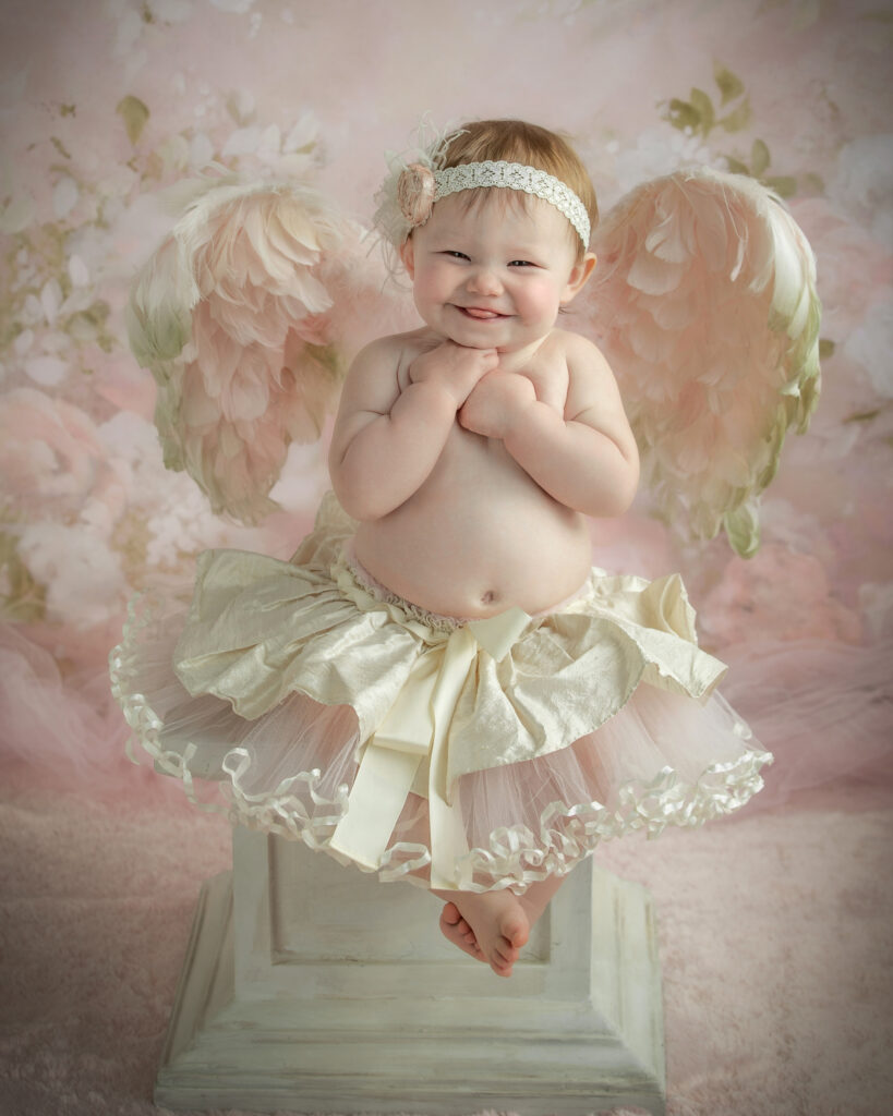 One-year-old girl angel portrait in soft pink floral setting at Studio C Fine Art Photography